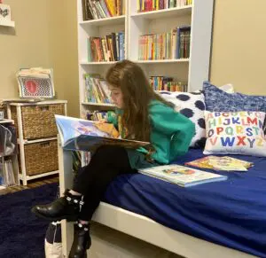 A girl sitting on top of a bed reading.