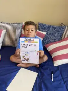 A boy sitting on the bed reading a book.