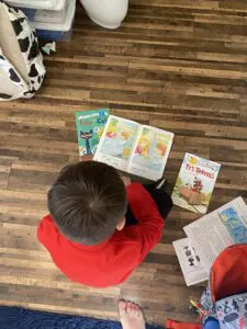 A boy sitting on the floor reading books.