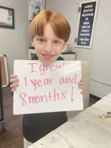 A boy holding up a sign that says i grew a year and a month.