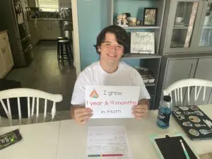 A boy sitting at a table holding a sign.