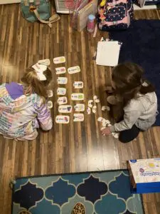 Two young girls playing a game on the floor.