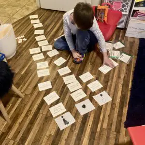 A boy playing with a stack of cards on the floor.