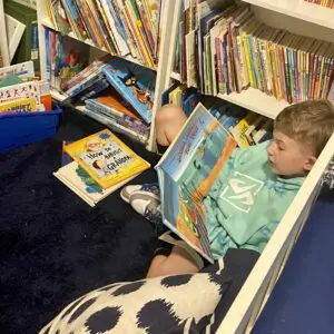 A boy is reading a book in a library.