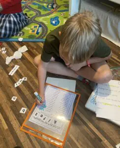 A boy is sitting on the floor with a piece of paper in front of him.