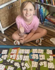 A little girl sitting on the floor with a stack of cards.