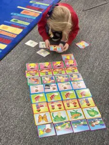 A little girl playing with a set of cards on the floor.
