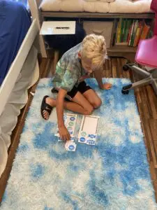 A young boy sitting on a blue rug playing a game.