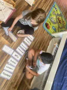 Two children playing with cards on the floor in a room.