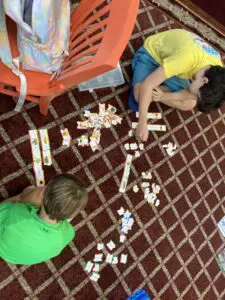 Two boys playing with puzzles on the floor.