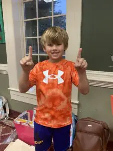 A young boy giving a thumbs up in a room.