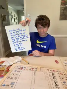 A boy holding up a piece of paper with writing on it.
